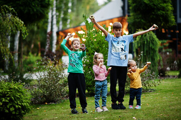 Obraz premium Four kids with doughnuts at evening yard. Tasty yummy donut food.