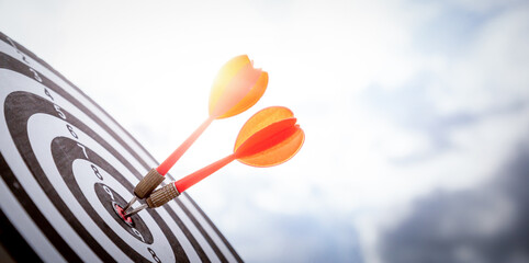 Close up shot red darts arrows in the target  of dartboard center on dark blue sky background. Business target or goal success and winner concept.