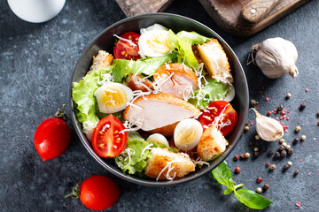 Caesar Salad with smoked chicken and parmesan on dark background. Top view