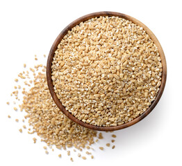 raw steel cut oats in the wooden bowl, isolated on the white background, top view