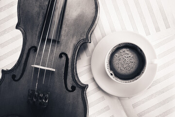 Violin acoustic classical stringed instrument and white coffee cup on sheet for musical notes