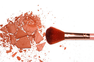 Creative photo of cosmetic swatches. Eye shadows in bronze colour broken and make up brush on a white background 