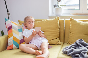 Portrait of toddler girl addictive on smartphone. Child look at cellphone screen play online game on gadget.