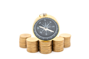 Business, Money Direction and Planning Concept. Closeup of vintage compass on stack of gold coins with white background.