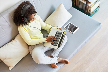 Afroamerikanische Frau auf dem Sofa am Laptop Computer