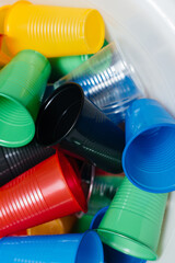 A large pile of multicolored plastic cups scattered on the floor. Pollution of the environment by human waste