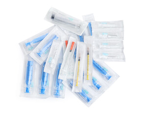 Different packed disposable syringes with needles on white background, top view