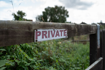 Shallow focus of a generic Private sign seen nailed to a wooden post at the edge of private gardens in London, UK.