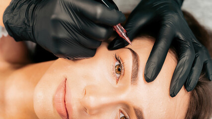 Make-up master performs the procedure of permanent eyebrow makeup