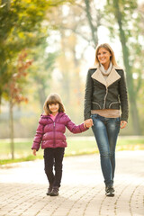 Obraz premium Mother and daughter walking in park in autumn.