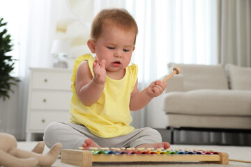 Cute little redhead baby playing with xylophone at home