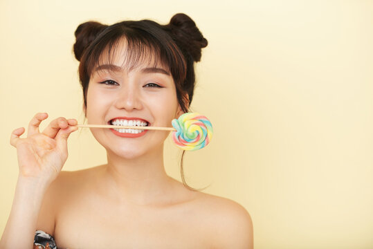 Funny beautiful young woman holding swirl lollipop on wooden stick in her mouth