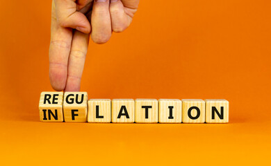 Inflation or regulation symbol. Businessman turns cubes and changes the word inflation to regulation. Beautiful orange table, orange background, copy space. Business, inflation or regulation concept.