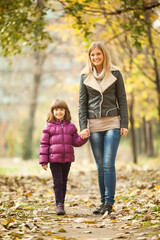 Fototapeta premium Mother and daughter walking in park in autumn.