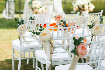 Chairs for a wedding ceremony decorated with pink flowers