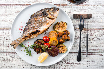 dorada grilled fish and vegetables on a plate top view, flat lay