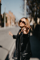 Fototapeta premium Young girl in leather jacket and jeans resting outdoors. portrait of woman in the city