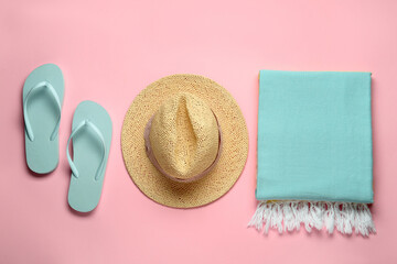 Beach towel, flip flops and straw hat on pink background, flat lay