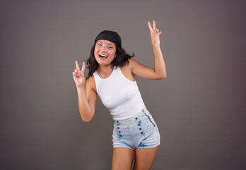 smiling young chinese girl with bandana and shorts, making the peace or victory sign, in a funny...