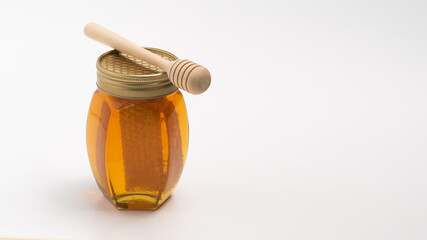 Honey in a jar with honey piece on white background.