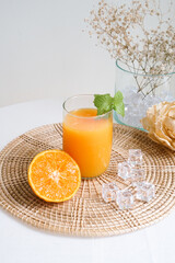 Glass of fresh organic orange juice which decorate with green peppermint leaves. Concept photo for healthy and detox drink or beverage. Fresh Orange juice on light background with copy space for text.