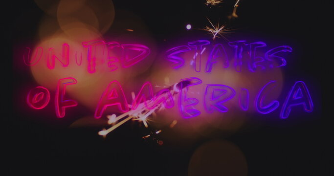 Image of glowing sparkler and united states of america text in neon glowing letters