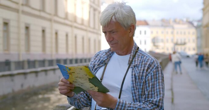 Senior male tourist exploring town with map