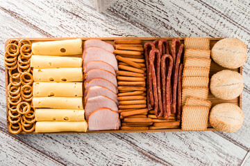 Antipasto cold meat dish with breadsticks, prosciutto, ham, ham slices and cheese on a wooden tray