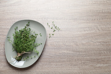 Bunch of aromatic thyme on wooden table, top view. Space for text