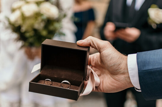 Selective focus image of best man holding box with wedding rings.