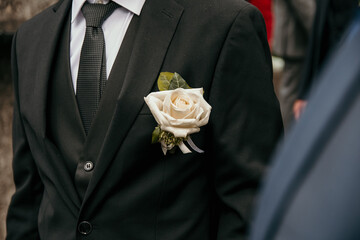 Selective focus photo of white rose on groom's suit on wedding day. - obrazy, fototapety, plakaty