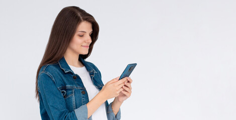 Pleased brunette woman writing message on smartphone over white background
