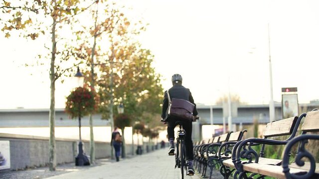 a rear view of businessman commuter with electric bicycle traveling to or from work