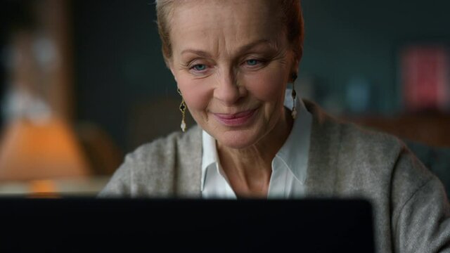 Portrait of sentimental old woman looking computer screen in luxury interior.