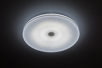 Ceiling round LED illuminator on a dark background. Modern lighting fixtures for the room.