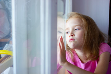 sad girl in a pink dress sits by the window, loneliness concept, isolation