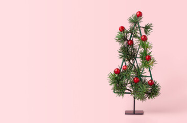 Minimal holiday card with a small metal  Christmas tree decorated with fir branches and red ilex berries