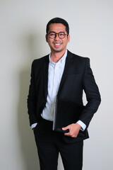 Young Asian business man smiling confident while holding laptop computer