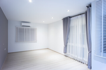 Empty room or bedroom at night. Interior inside house consist of wooden laminate floor, white gray wall, air conditioner, curtain and adjusting vertical blinds. New clean look modern for background.