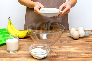 Caucasian woman chef in apron preparing ingredients for making cottage cheese banana muffins cupcakes casserole at home kitchen cuisine, online cooking, recipe instruction