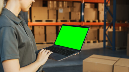 Female Manager Using Green Screen Chroma Key Laptop. In the Background Warehouse Retail Center with...