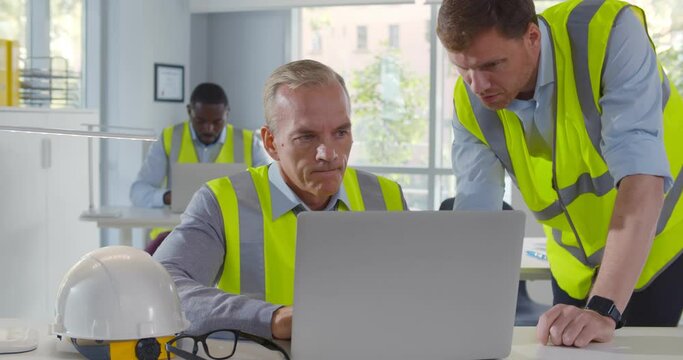 Two male architects working on laptop in office