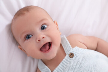 Cute little baby lying on white blanket, top view
