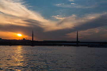Fototapeta na wymiar トルコ　イスタンブールの金角湾にかかるアタチュルク橋と夕焼けでオレンジに染まった空
