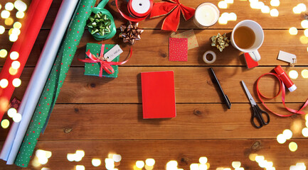holidays, new year and christmas concept - different stuff for gifts wrapping on wooden table over festive lights