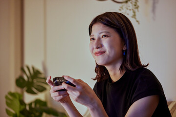 リビングでゲームをする若い日本人女性 © west_photo