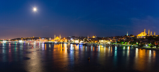 Fototapeta premium トルコ イスタンブールの金角湾の夜景と旧市街にあるニューモスクと丘の上に建つスレイマニエ・モスク