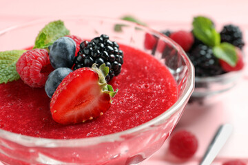 Delicious panna cotta with fruit coulis, fresh berries and mint in dessert bowl, closeup