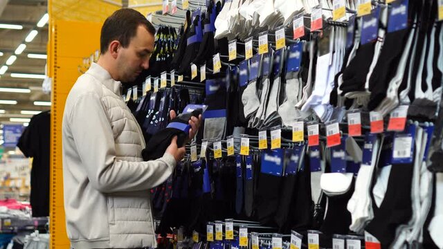 Men's socks on a shelf in a supermarket. Man choosing socks in a store