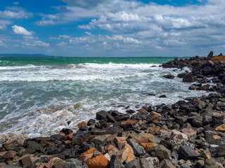 Fototapeta na wymiar Rocky coast with waves at the Black Sea against cloudy sky in Pomorie, Burgas Bay, Bulgaria.